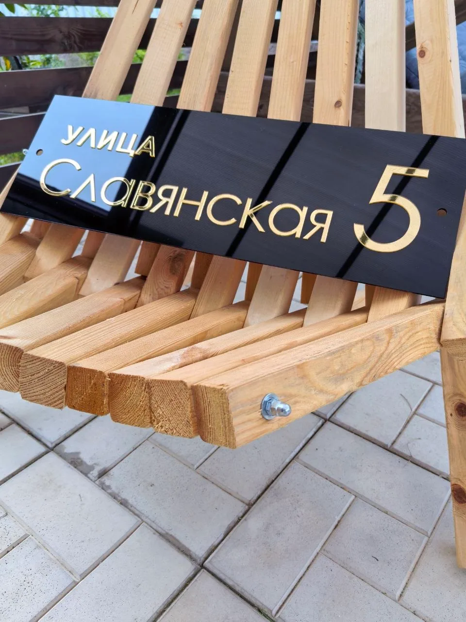 Прямоугольная черная глянцевая табличка с объемными золотыми буквами и цифрой 5, закрепленная на деревянном основании