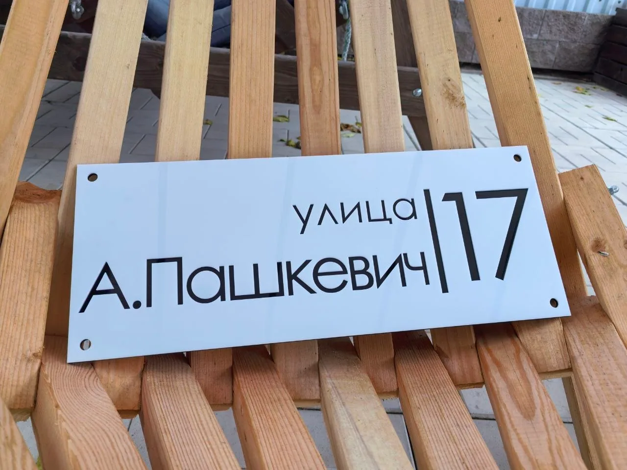 Белая прямоугольная адресная табличка с черным номером 17 и названием улицы А. Пашкевич, минималистичный дизайн