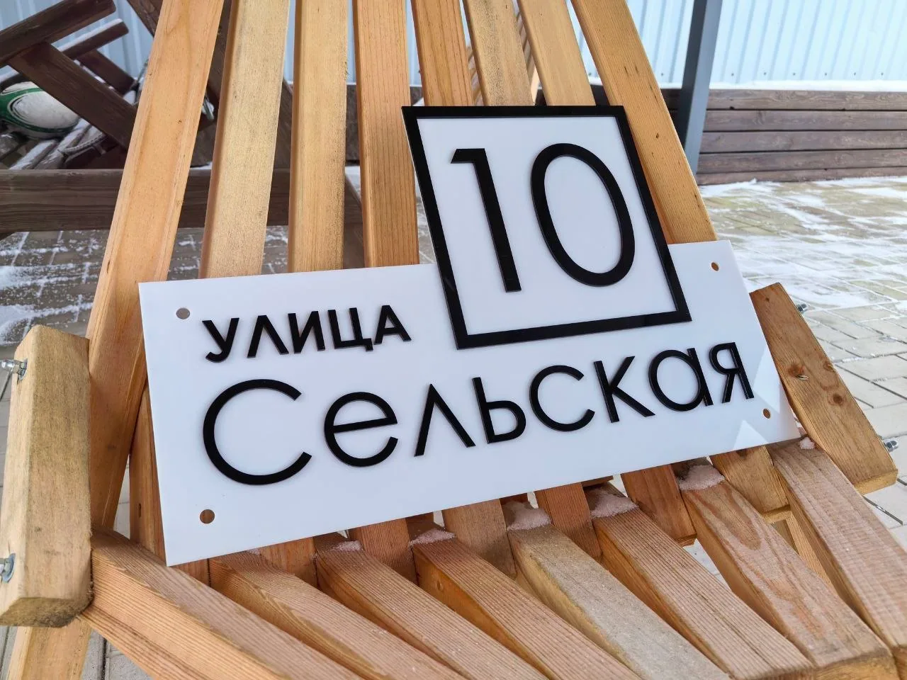 Белая фигурная табличка из акрила с объемным черным номером 10 в рамке и накладными буквами улицы Сельская